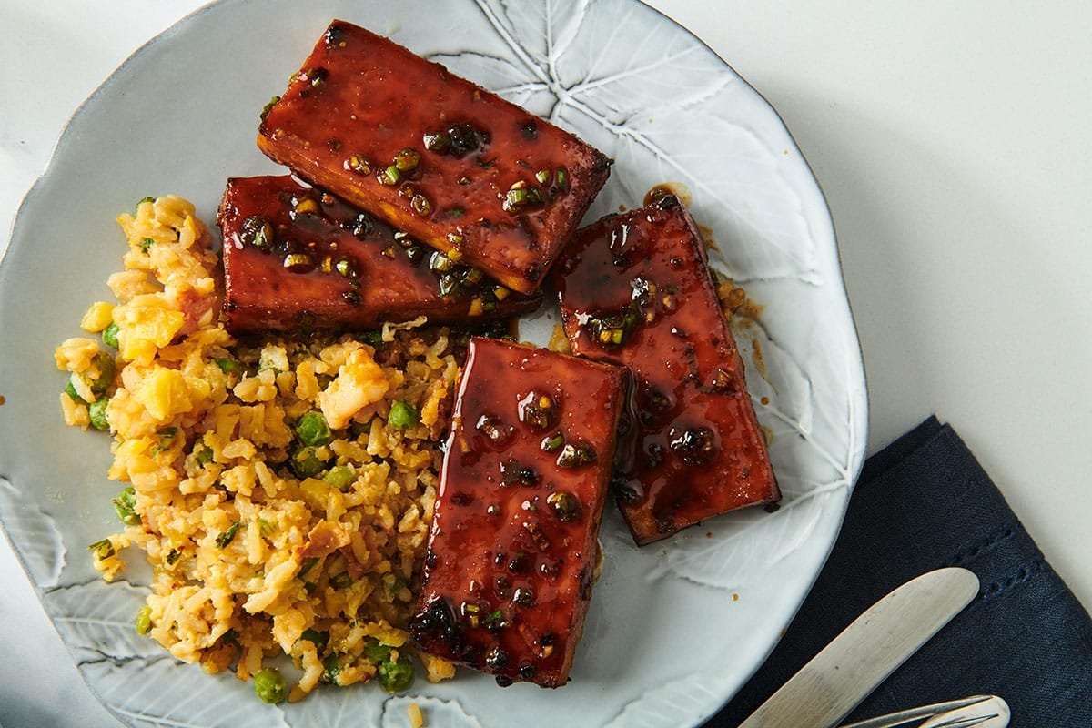 Air-fried tofu with sticky Chinese barbecue sauce on white plate with sides.