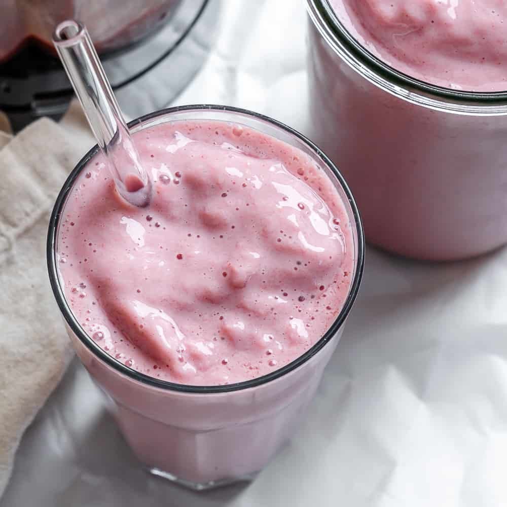 two glasses of completed Strawberry and Pineapple Smoothie on a white surface